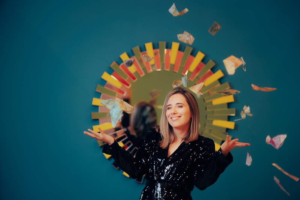 Smiling woman in a sequined outfit joyfully throws paper money. A colorful, mirrored pattern is on the wall behind her, creating a lively atmosphere.